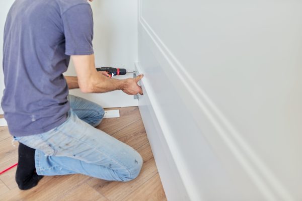 Close up detail of furniture and hands of carpenter worker with professional tool, screwdriver in hand, assembling furniture at home. Renovation, new furniture, work carpentry process